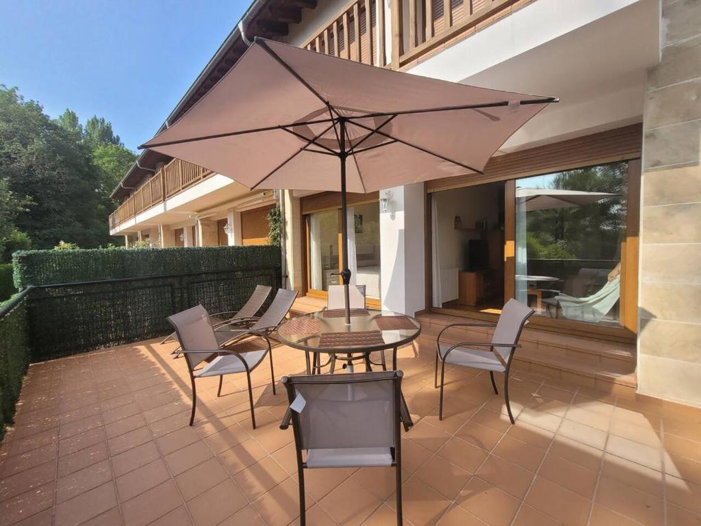 a patio with a table and chairs and an umbrella at PEBA Nudo del Ocho Apartamento en Tina Menor in Pesués