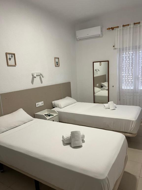 a hotel room with two beds and a mirror at Hotel Bennington in La Marina