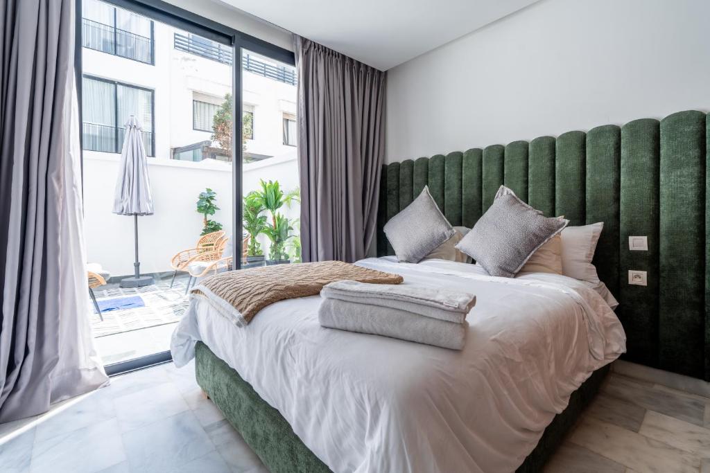 a bedroom with a large bed with a green headboard at Studio Ferme Bretonne, Bien Desservi & Salle Gym in LʼOasis