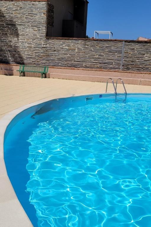une piscine bleue avec un banc en arrière-plan dans l'établissement La Bourboule, à Collioure