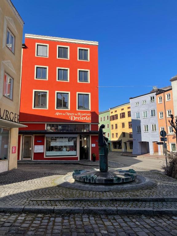 an orange building with a statue in the middle of a street at Ferienwohnung Dreierlei in Wasserburg am Inn