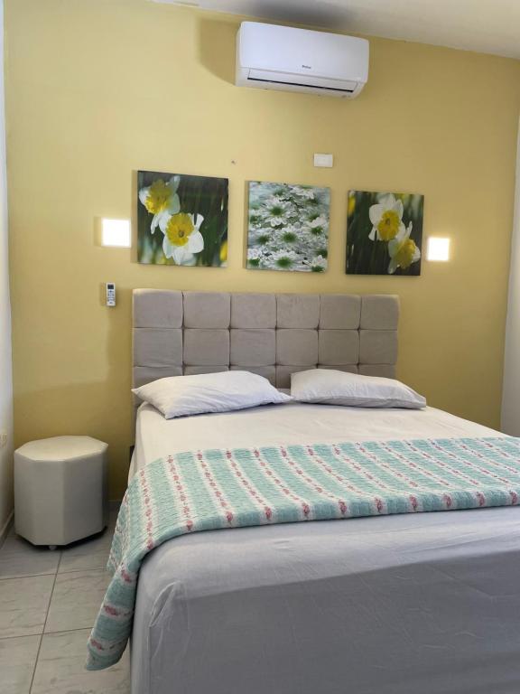 a bedroom with a bed with three pictures on the wall at Casa de Praia Tamandaré in Tamandaré
