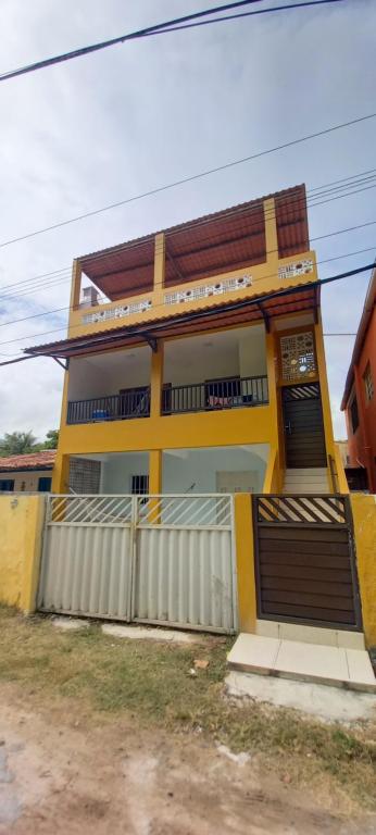 ein gelbes Haus mit einem Zaun davor in der Unterkunft Yellow House Itapuama in Cabo de Santo Agostinho