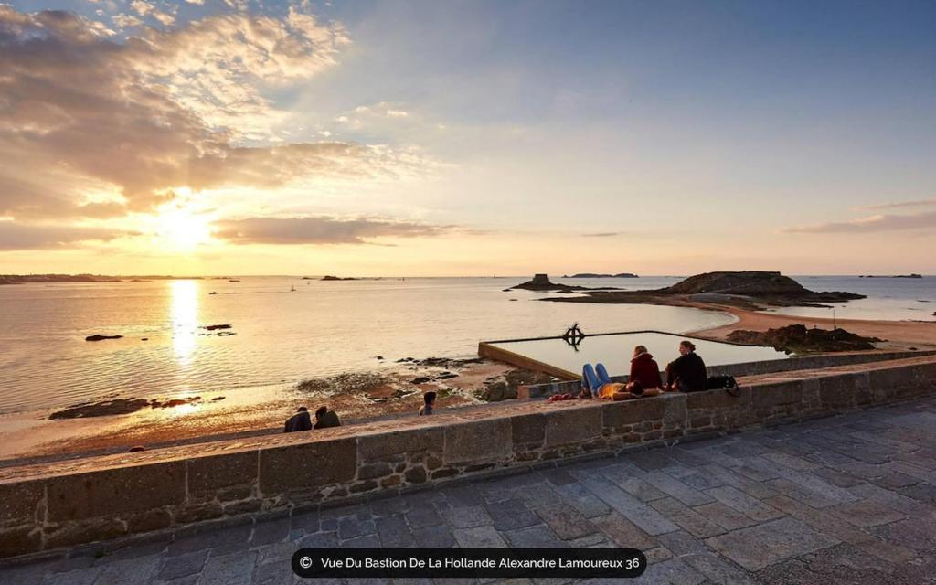 a group of people sitting on a wall looking at the ocean at T2 dans l'intra-Muros VUE MER exceptionnelle in Saint Malo