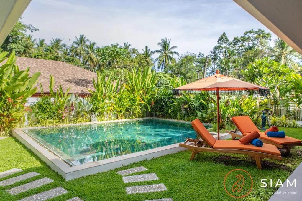 a swimming pool with an umbrella and two chairs and an umbrella at Villa Sumalee 3Br Private Pool 8 mins to Beach in Koh Samui