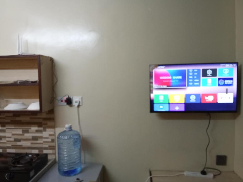 een televisie aan een muur met een fles water bij Raicy Bnb in Bamburi