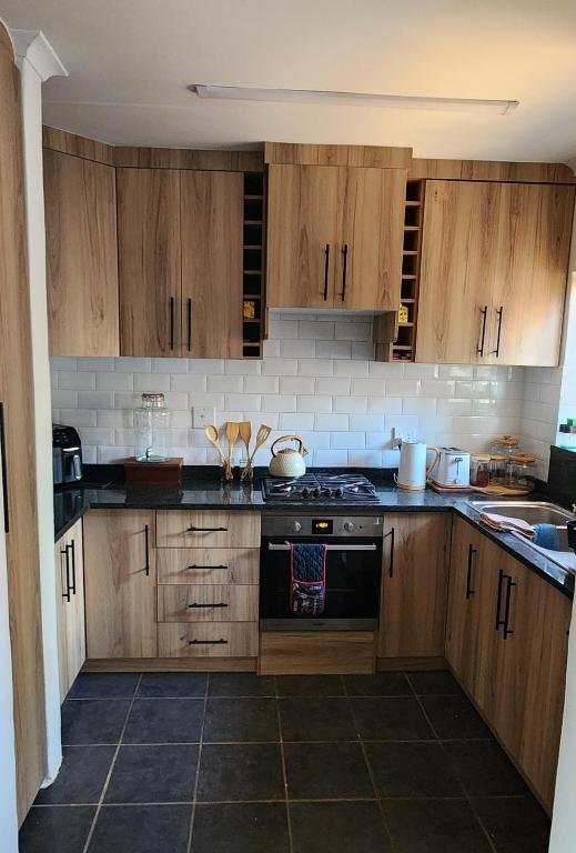 a kitchen with wooden cabinets and a stove top oven at The Cozy Corner in Potchefstroom