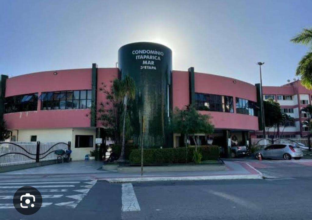 a large pink building with a sign in front of it at Apartamento para temporada 2 quartos coqueiral de itaparica in Vila Velha