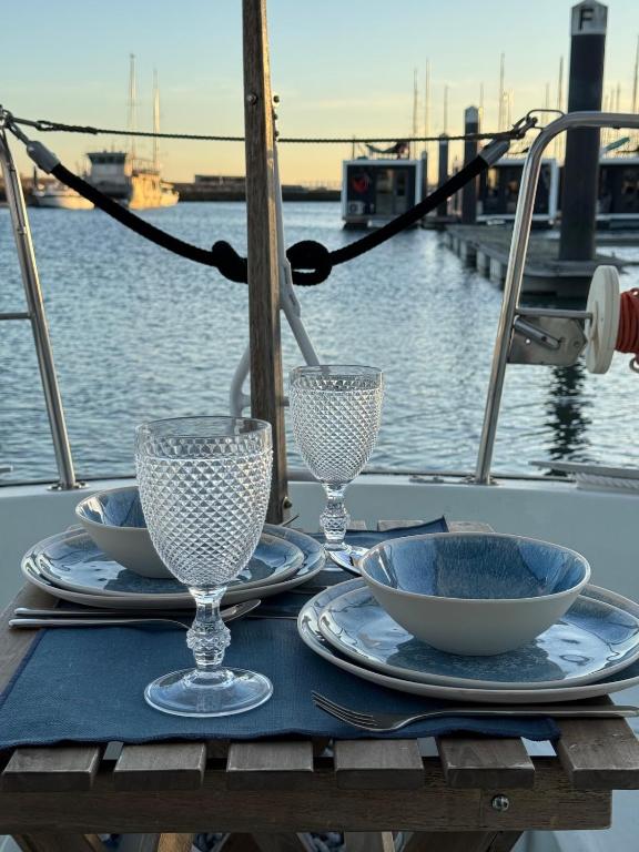 a table with plates and wine glasses on a boat at Charming Sailboat in Lisbon