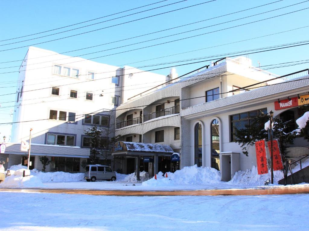 una calle cubierta de nieve frente a un edificio en Hotel Grace Hakuba en Hakuba