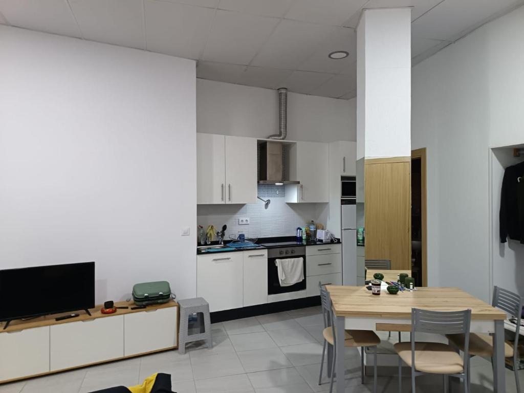 a kitchen with white cabinets and a table with chairs at Finisterrae Centro in Finisterre