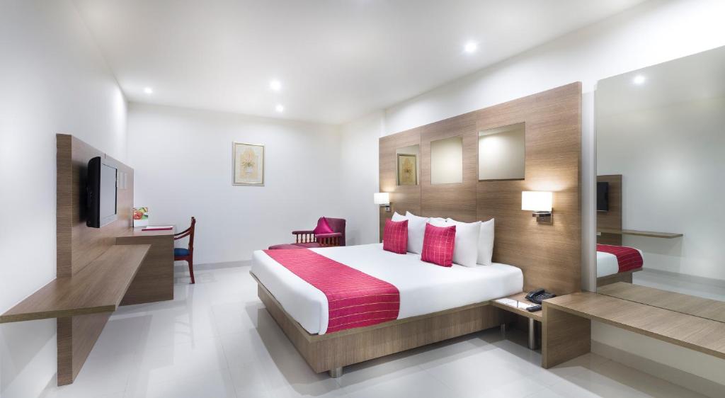 a hotel room with a bed and a desk at Regency Tiruttani by GRT Hotels in Tiruttani