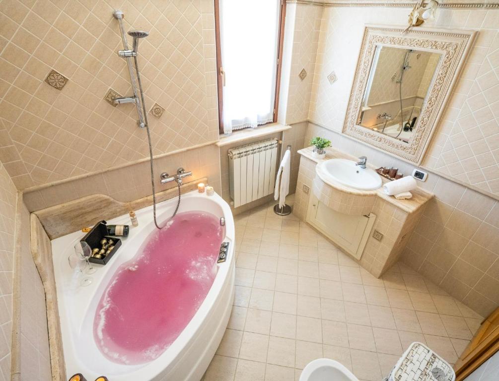 y baño con bañera rosa y lavamanos. en Villa Antonella Wellness & Jacuzzi, en Ciampino
