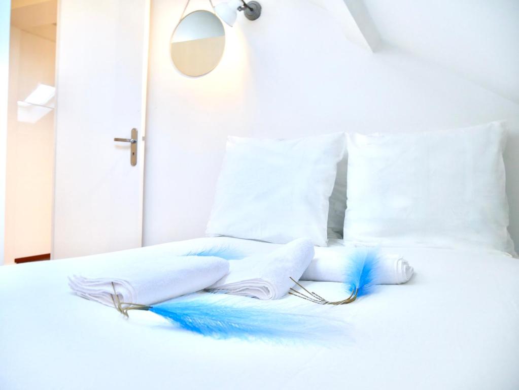 - un lit blanc avec des draps et des oreillers bleus et blancs dans l'établissement Céleste Home, à Melun