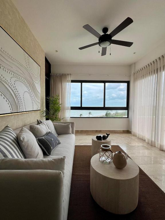 a living room with a couch and a ceiling fan at Penthouse Navela 405 by Cercana in Telchac Puerto