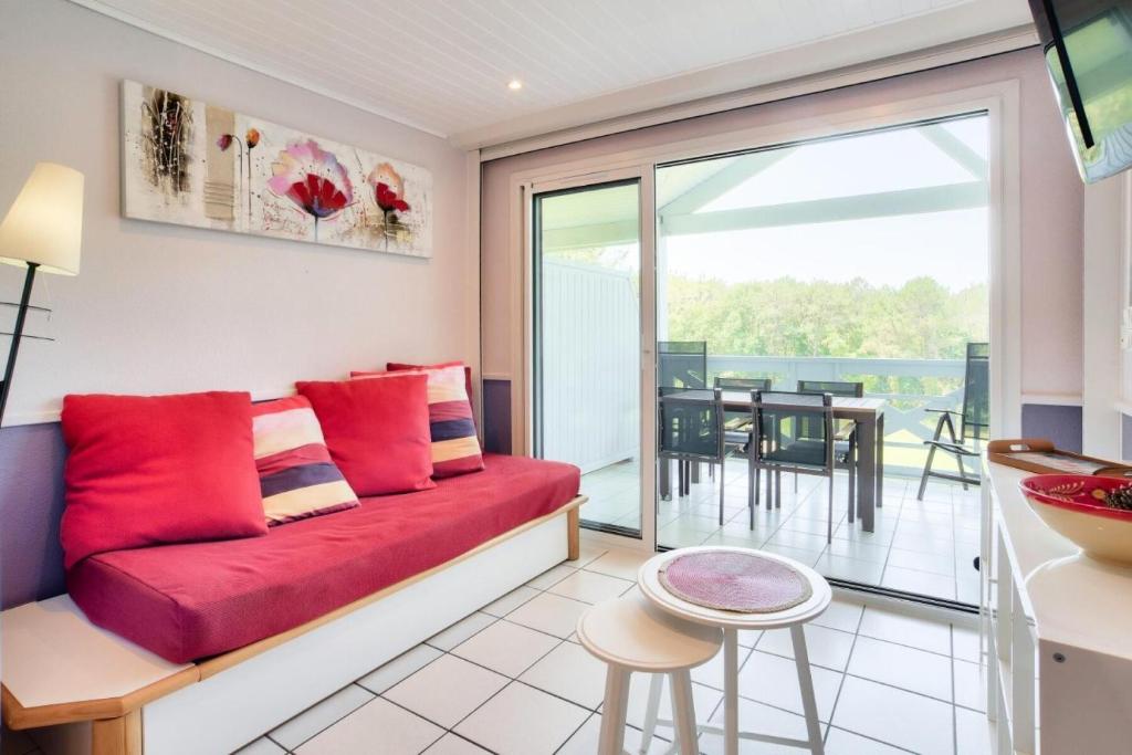 un salon avec un canapé rouge et une table dans l'établissement Village Moliets - maeva Home - Appartement 3 pièces 5 personnes - Sélection MAE-6641, à Moliets-et-Maa