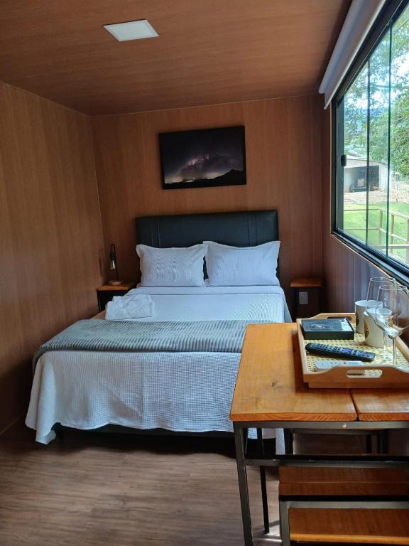 a bedroom with a bed and a table and a table sidx sidx at Vibe Coffee Container CATUAÍ VERMELHO in Pedra Menina