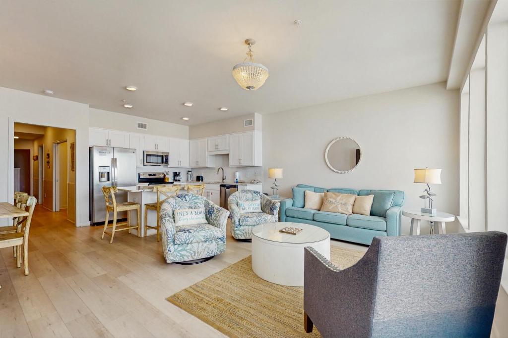 Una sala de estar con un sofá azul y una cocina. en Sea Glass 203- No Worries, en Gulf Shores