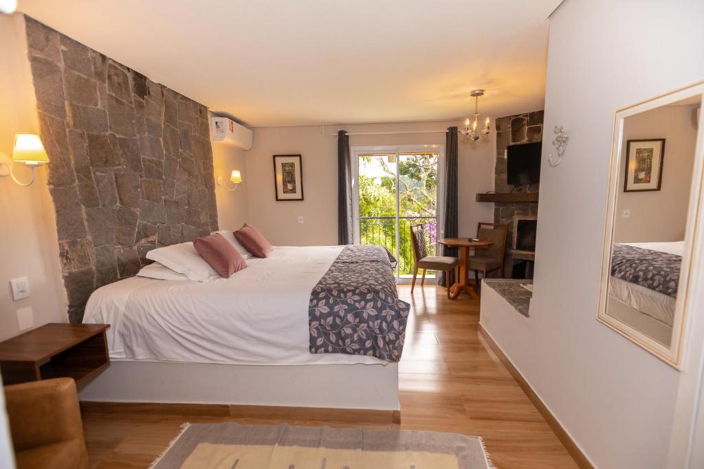 une chambre avec un lit avec un mur en pierre dans l'établissement Villa Hegus no Alto da Boa Vista, à Campos do Jordão