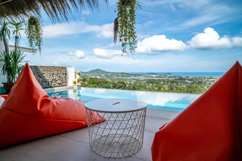 a patio with a table and chairs and a swimming pool at Villa Samurai Panoramic Sea & Jungle Views in Bophut 