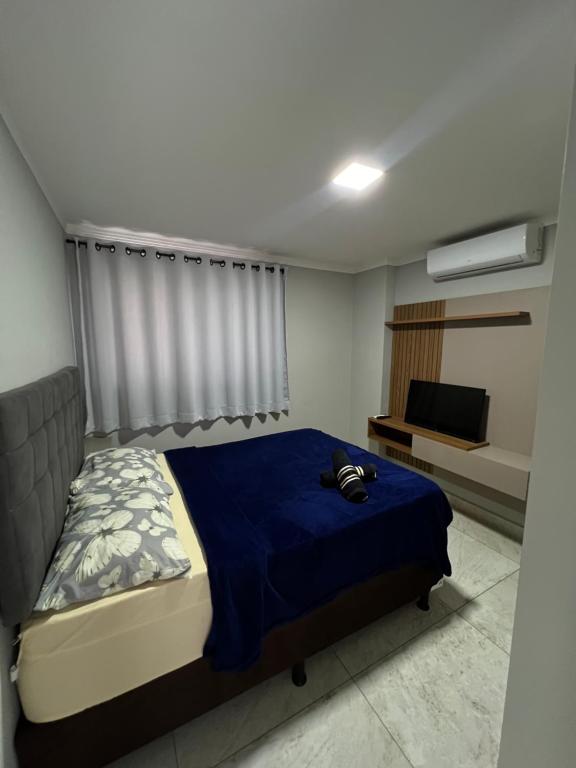ein Schlafzimmer mit einem blauen Bett und einem TV in der Unterkunft Flat de alto padrão ar condicionado piscina e academia in Campina Grande