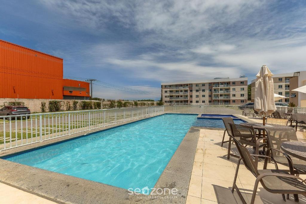 a swimming pool with chairs and a building at Apto 450m da Praia em Cond. c/ Piscina VAR0302 in Cururupe