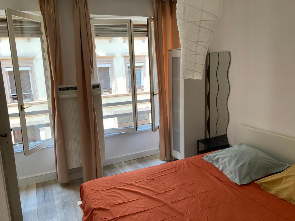 - une chambre avec un lit orange et 2 fenêtres dans l'établissement STRASBOURG PROCHE Petite France, à Strasbourg