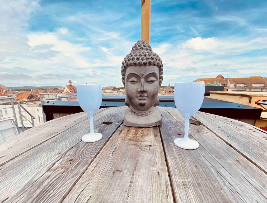 une statue assise sur une table avec deux verres à vin dans l'établissement Appartement coup de coeur, à Le Touquet-Paris-Plage