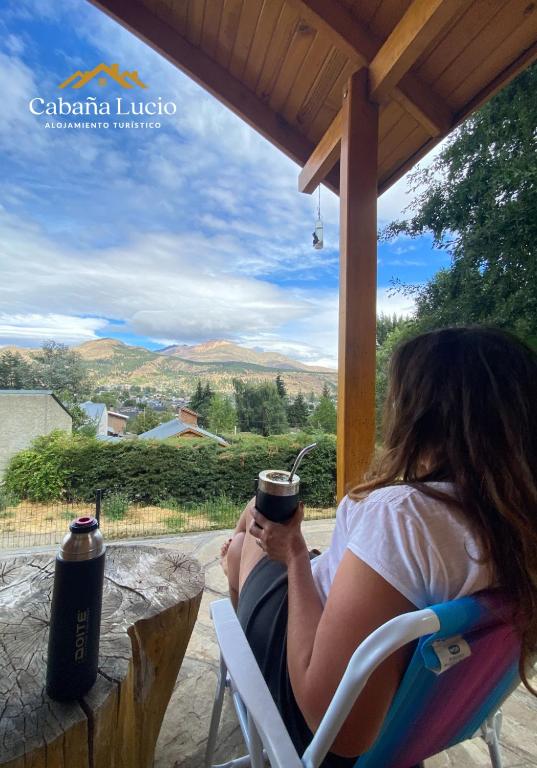 a woman sitting in a chair holding a cup of coffee at Cabaña Lucio in Esquel