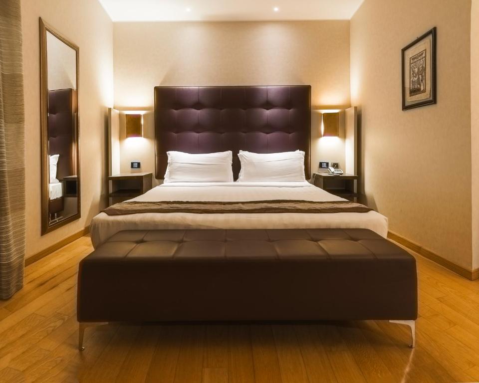 a bedroom with a large bed with a large headboard at Rome Airport Hotel Fiumicino in Fiumicino
