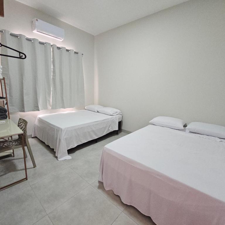 a bedroom with two beds and a chair and a window at Casa Nova 02 in Primavera do Leste