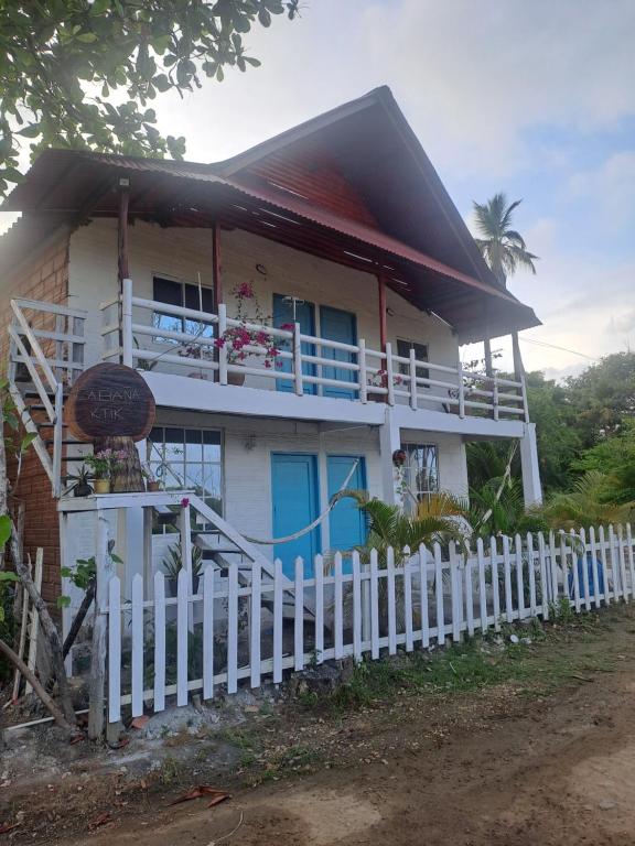 a house with a white fence in front of it at Apart Cabaña KTIK in San Bernardo del Viento