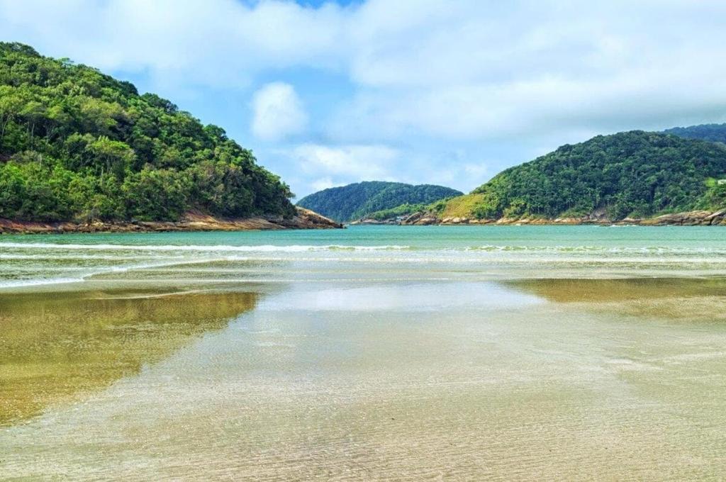 a view of a beach with mountains in the background at Recanto da Familia in Guarujá