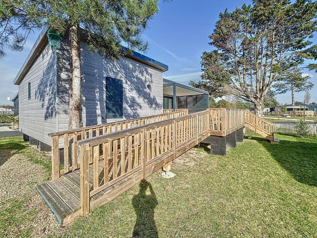 une femme debout sur un pont en bois devant une maison dans l'établissement Chalet de standing à Jullouville - 6 couchages, piscine chauffée, proche plage et commerces, Wi-Fi gratuit - FR-1-361-449, à Jullouville