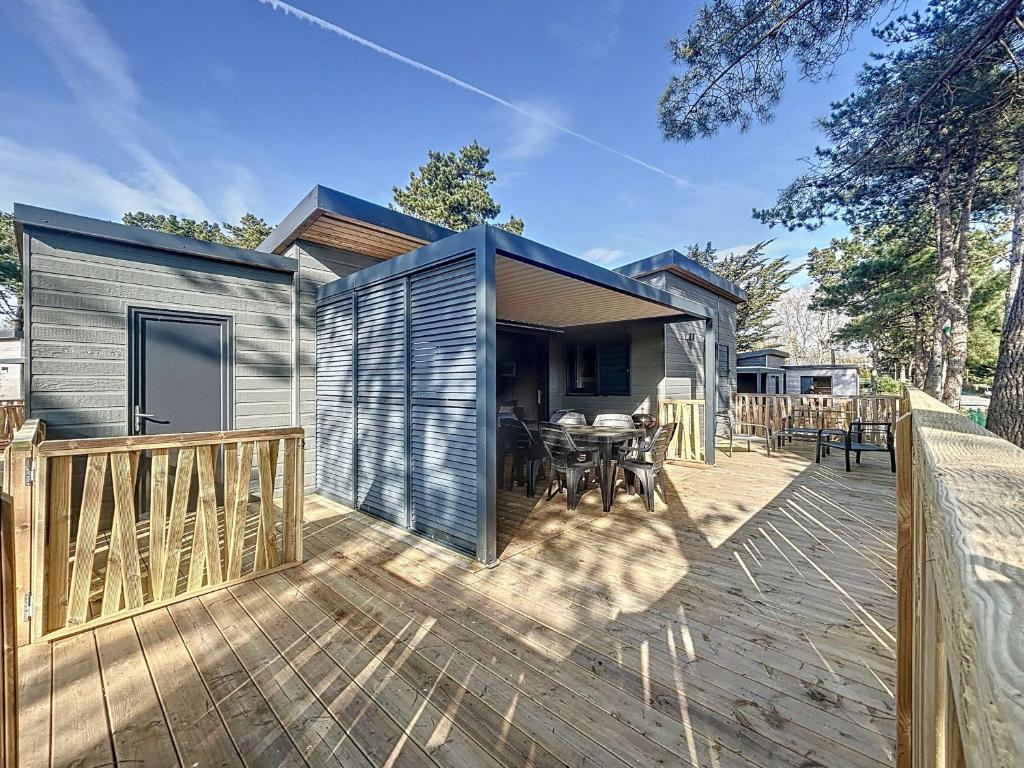 une petite maison sur une terrasse avec une table dans l'établissement Chalet de Standing à Jullouville: 6 Couchages, Piscine Chauffée, Proche Plage et Commerces, WiFi Gratuit - FR-1-361-548, à Jullouville