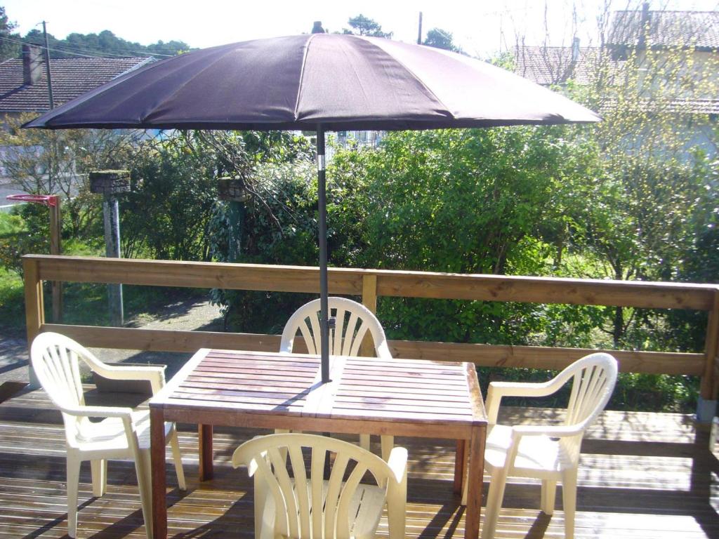 une table en bois avec des chaises et un parasol dans l'établissement Maison landaise spacieuse pour 12 pers. à Capbreton avec jardin - FR-1-239-1101, à Capbreton