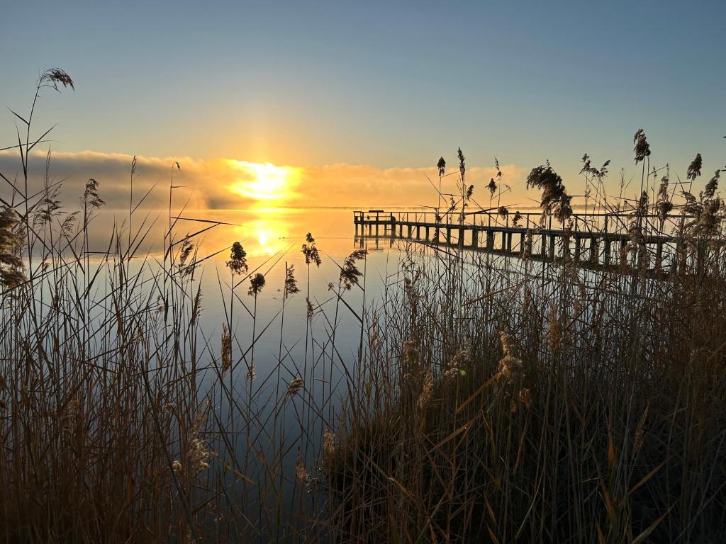 a sunset over a body of water with a pier at The Jetty Hut - Lake Frontage Barmera Riverland in Barmera