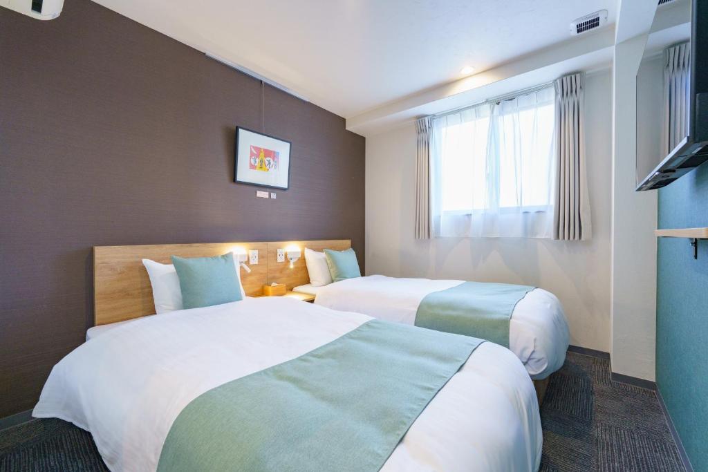 a hotel room with two beds and a window at USP HOTEL Shinimamiya in Osaka