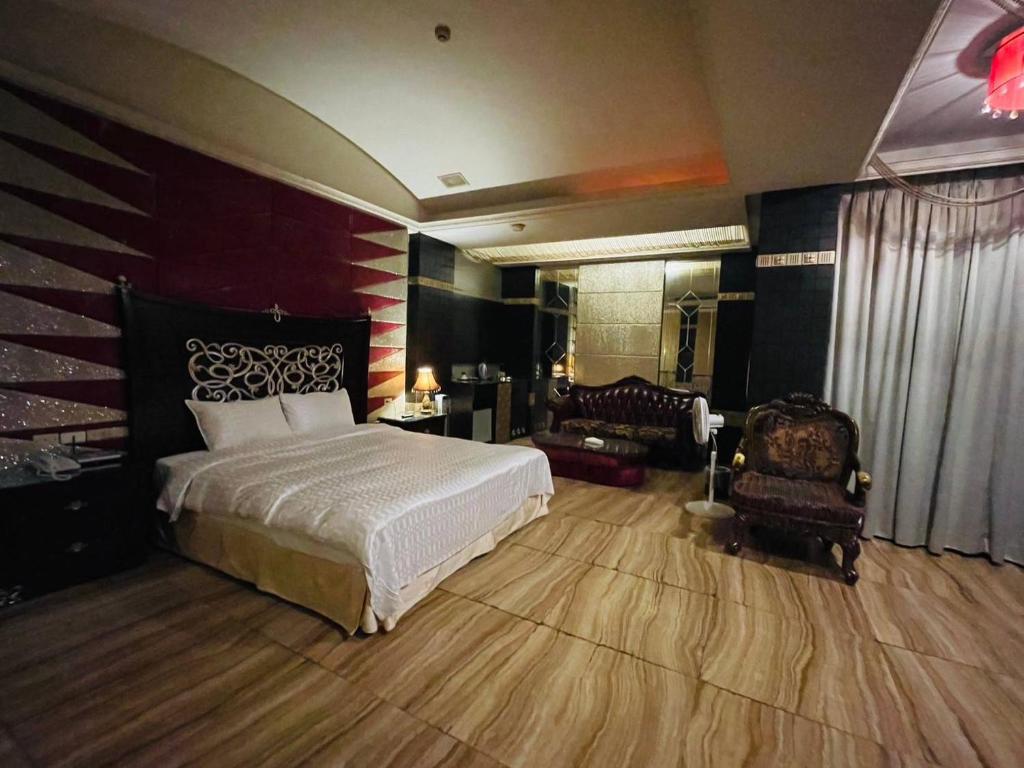 a bedroom with a bed and two chairs in it at 嘉義永鎮御花園汽車旅館 in Chiayi City