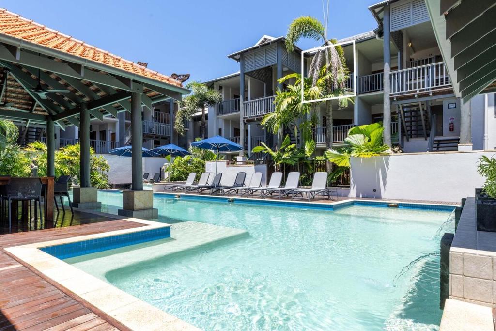a swimming pool at a resort with chairs and umbrellas at Hibiscus POOL VIEW Villa 49b in Port Douglas