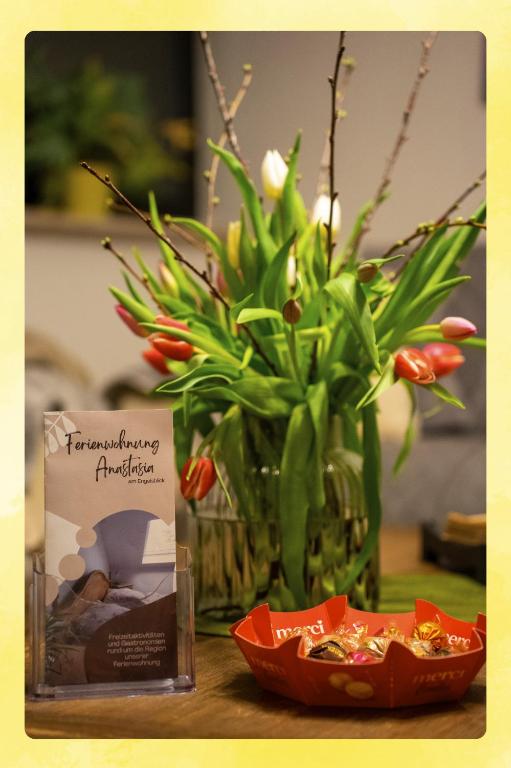 a table topped with a vase with flowers and a box at Ferienwohnung Engelsblick in Kreuzau