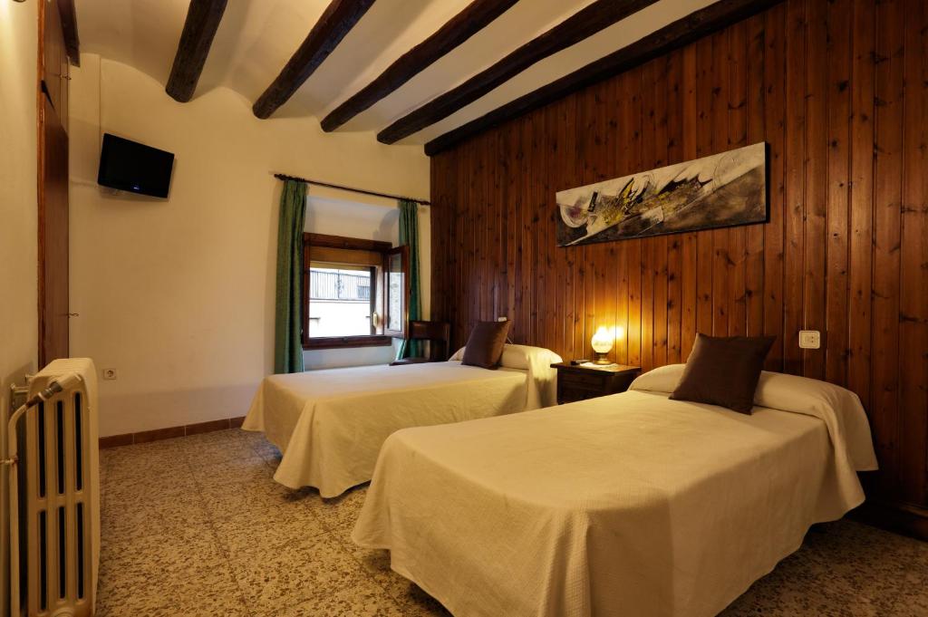 2 camas en una habitación con paredes de madera en Hostal Populetus en Poboleda