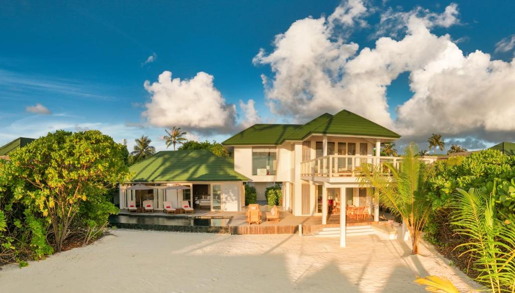 a house with a green roof on a beach at Siyam World Maldives - 24-Hour Premium All-inclusive with Free Transfer in Dhigurah