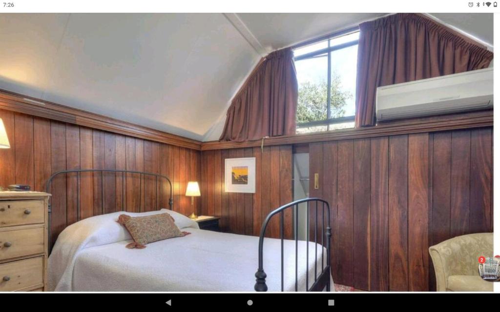 a bedroom with a bed with wooden walls and a window at Snow white's 2 bedroom dream Cottage with free parking in Perth