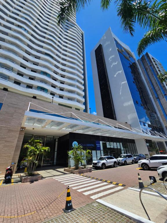 a building with cars parked in front of two tall buildings at Bahia Astron Mundial Hotel Flats in Salvador