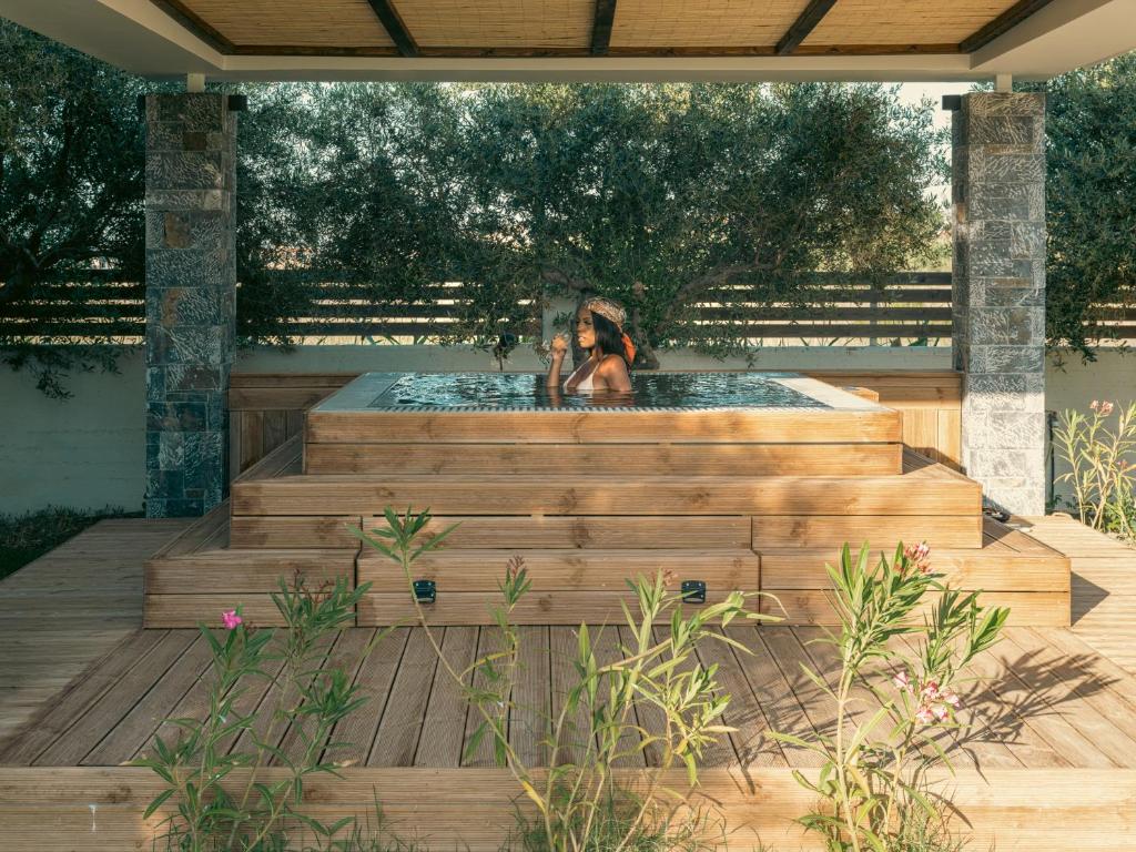 a woman sitting in a hot tub on a wooden deck at Malena Hotel & Suites - Adults Only by Omilos Hotels in Amoudara Herakliou