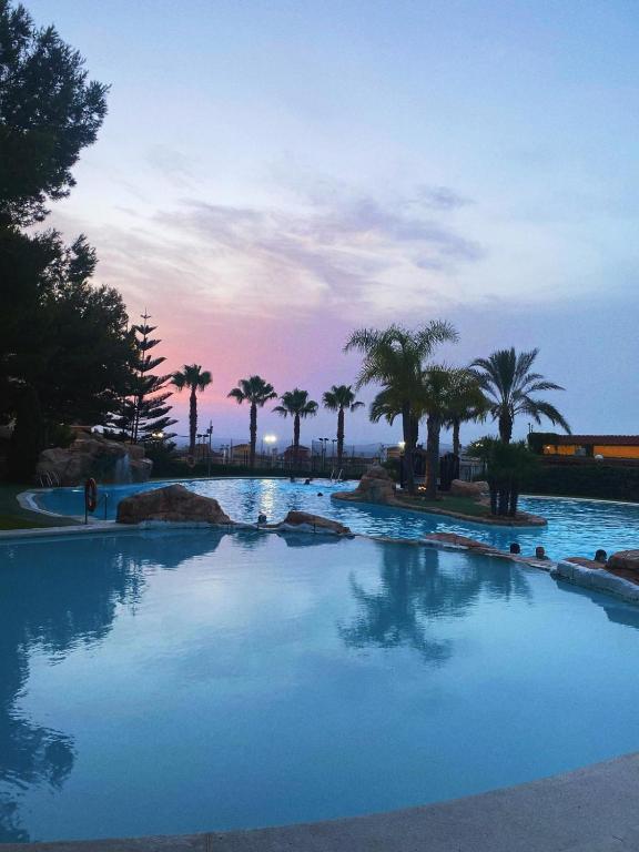 a large swimming pool with palm trees in the background at Casa Monte y Faro in Santa Pola