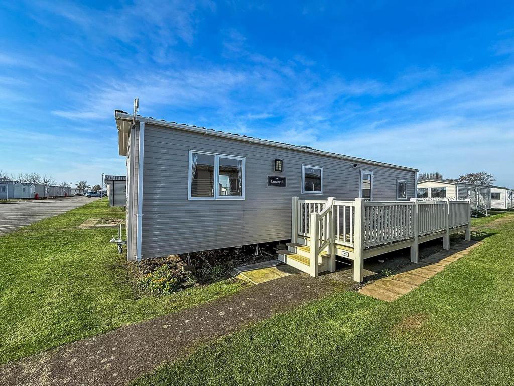a tiny house with a porch and a fence at Cosy Caravan With Decking At Golden Sands Haven Holiday Park Ref 63009Rc in Mablethorpe