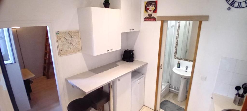 - une petite salle de bains blanche avec lavabo et miroir dans l'établissement Appartement calme aux abords de Paris, Seine, à Boulogne-Billancourt