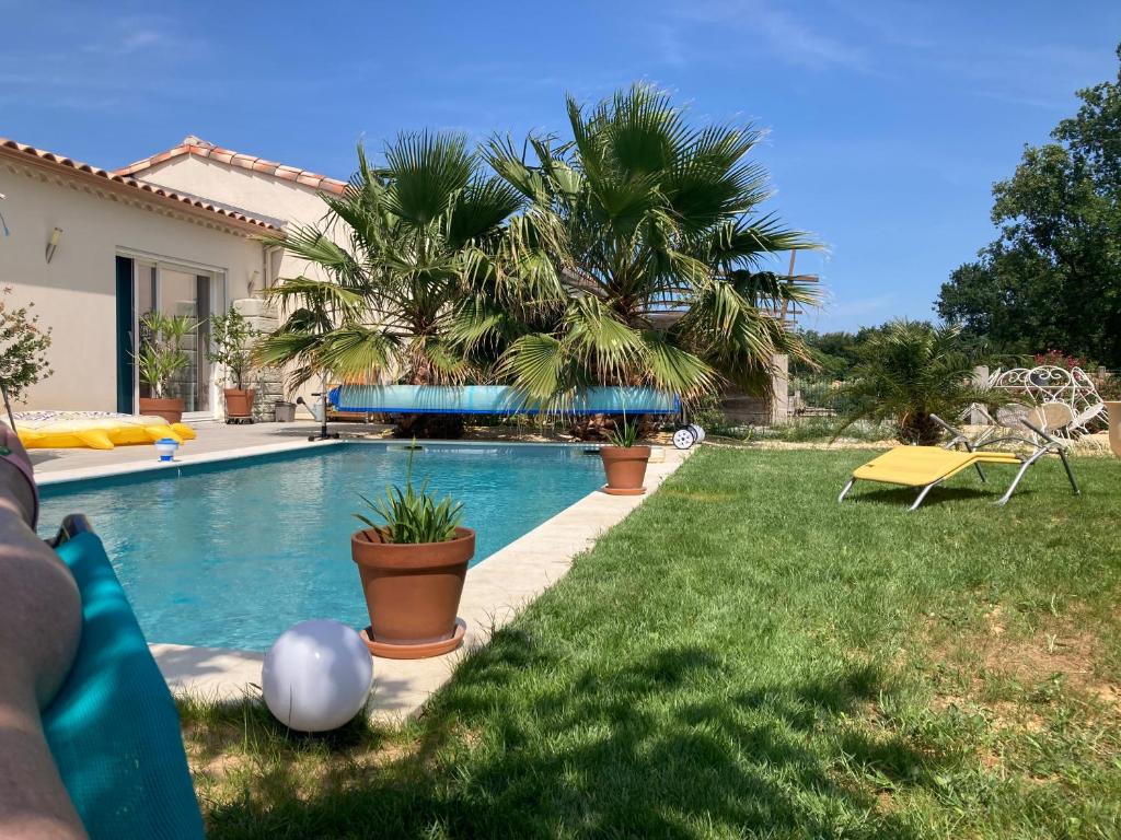 une maison avec une piscine et une cour dans l'établissement La maison aux palmiers, à Arpaillargues-et-Aureillac